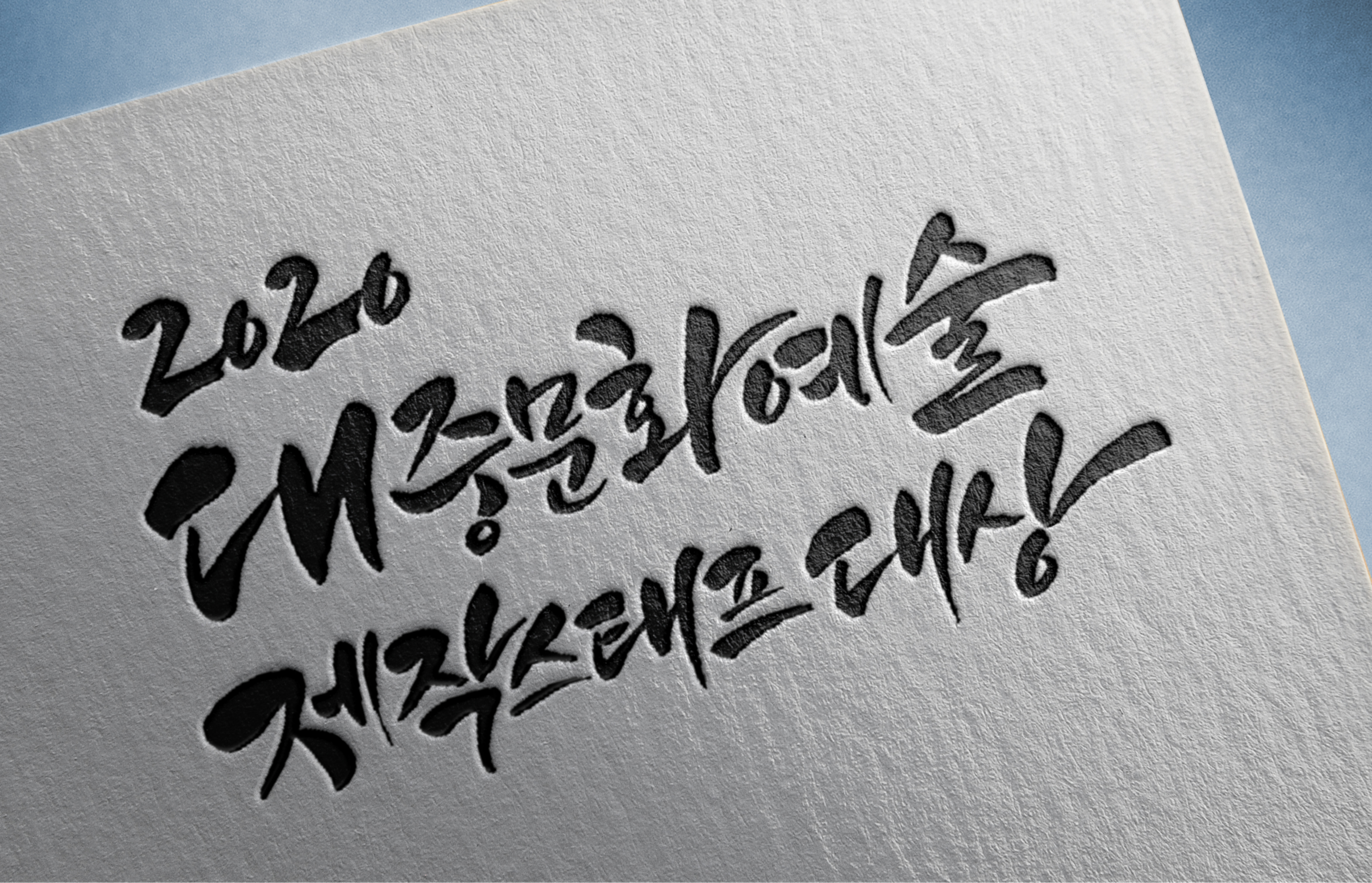 흰색 종이 위에 검은색 붓글씨로 2026과 한글 문구가 적혀 있다.